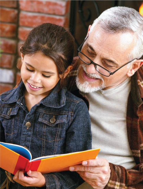 Grandfather reading a book to his granddaughter.