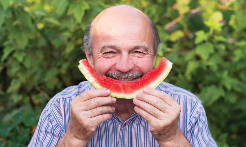 man eating a slice of watermelon in a smile shape